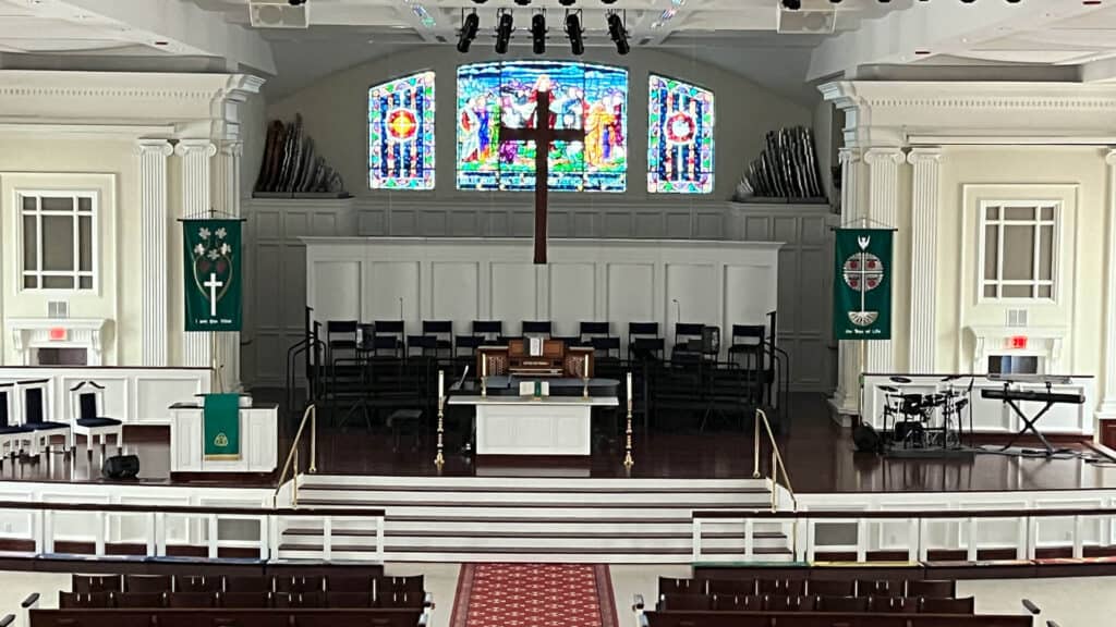 Sanctuary chancel at First United Methodist Church of Sarasota, with stained glass windows, wooden cross, and altar — available for weddings.