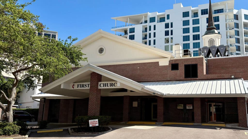 Exterior of First United Methodist Church of Sarasota showing the Mira Mar Court entrance with covered canopy, brick facade, and steeple.
