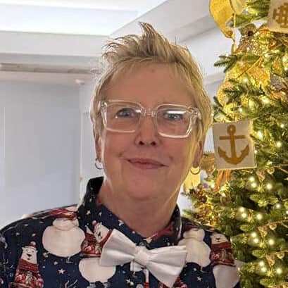 Staff member Tammy Ralston smiling beside a decorated Christmas tree at First United Methodist Church of Sarasota