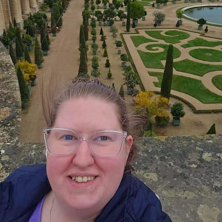 A staff member at First United Methodist Church of Sarasota smiles in a selfie taken at a formal garden.