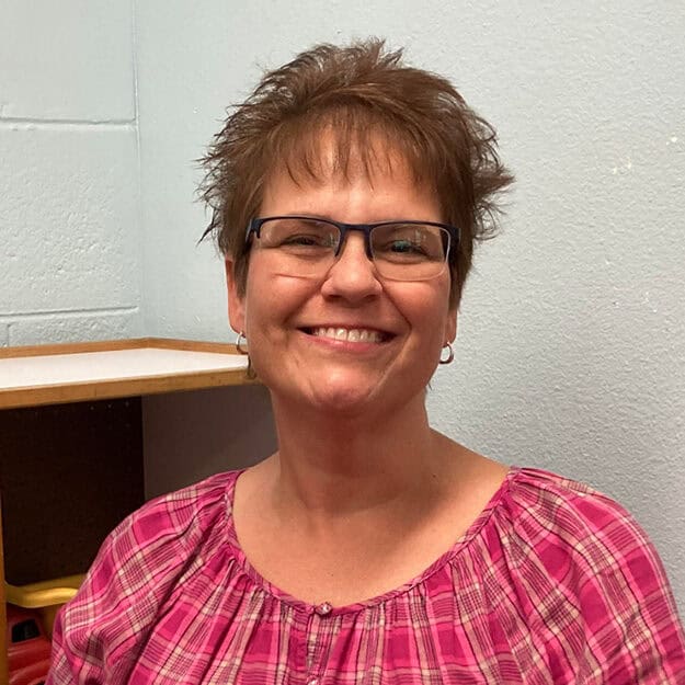 A staff member at First United Methodist Church of Sarasota smiles in a classroom setting.