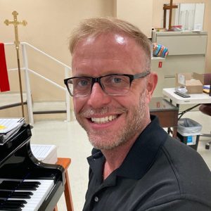 Michael Stuart, Music Fine Arts Director at First United Methodist Church of Sarasota, seated at a piano