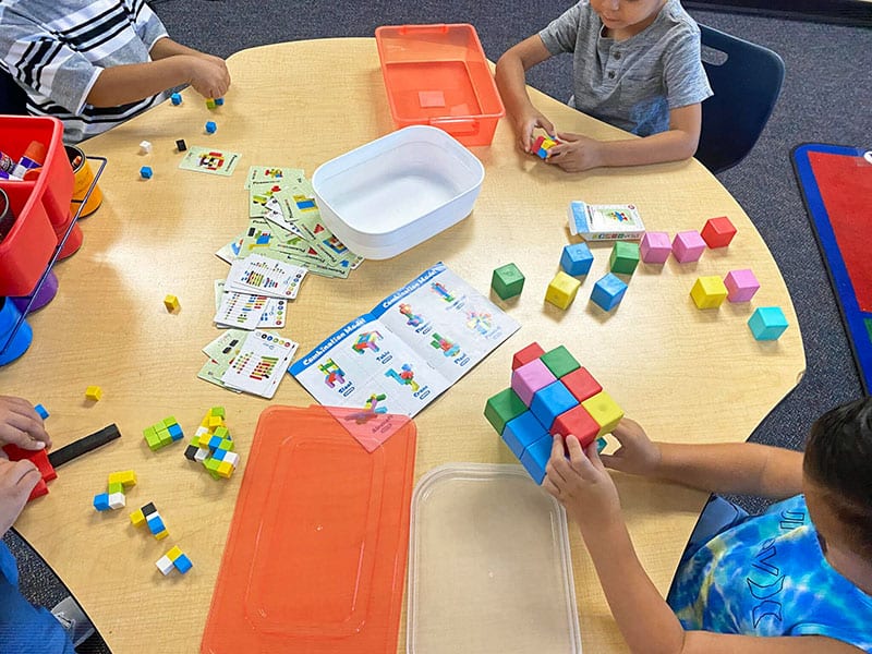 Children playing with colorful building blocks at early care center.